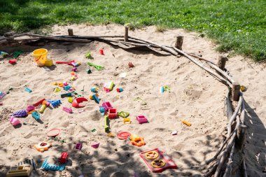 Ekolojik kum havuzu. Çimlerin yanında kum ve oyuncaklar. Kırsal kesimde eğitim, açık bir oyun alanında. Güneşli ve sıcak bir günde eğlence. Aktif çocukluk. Etkin yaşam biçimi