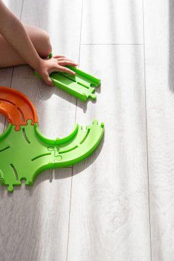 Bir çocuğun elleri yerde parlak renkli bir yapboz çocuk yolunu birleştiriyor. Metodoloji, öğretim yöntemi