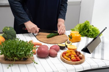 Kadın tablet cihazında yemek pişirirken yemek tarifi okuyor.
