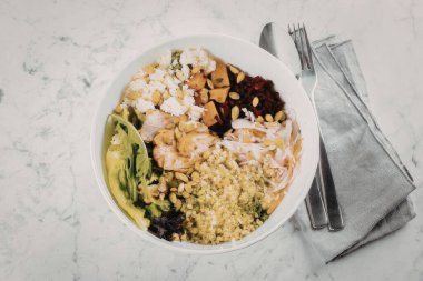 Mermer bir masada bir kase pirinç ve karışık sebzeler.