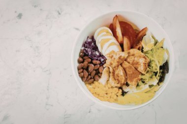 Tavuk, pirinç, fasulye ve çeşitli sebzelerle dolu besleyici bir kase..