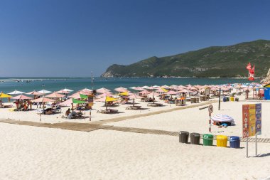 Setubal, Lizbon, Portekiz yakınlarında güneşli bir günde turist ve şemsiyelerle sahile güzel bir manzara