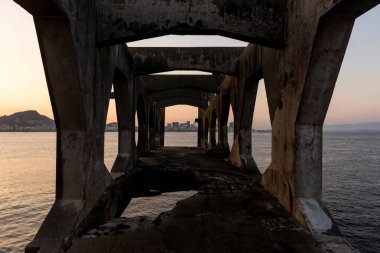 Rio de Janeiro, Brezilya 'daki kalenin beton yapısına çerçevelenmiş güzel okyanus gün batımı manzarası