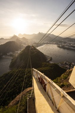 Sugar Loaf dağından Rio de Janeiro, Brezilya 'daki tramvaya, şehre ve okyanusa güzel altın gün batımı manzarası