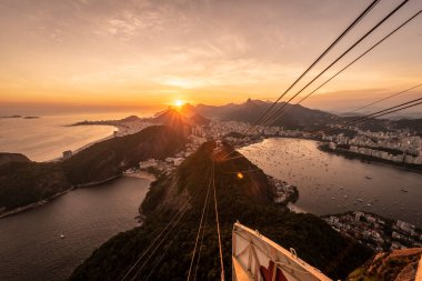 Sugar Loaf dağından Rio de Janeiro, Brezilya 'daki tramvaya, şehre ve okyanusa güzel altın gün batımı manzarası