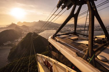 Sugar Loaf dağından Rio de Janeiro, Brezilya 'daki tramvaya, şehre ve okyanusa güzel altın gün batımı manzarası