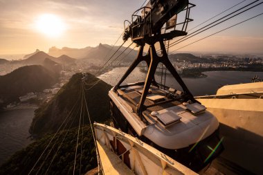 Sugar Loaf dağından Rio de Janeiro, Brezilya 'daki tramvaya, şehre ve okyanusa güzel altın gün batımı manzarası