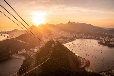 Sugar Loaf dağından Rio de Janeiro, Brezilya 'daki tramvaya, şehre ve okyanusa güzel altın gün batımı manzarası