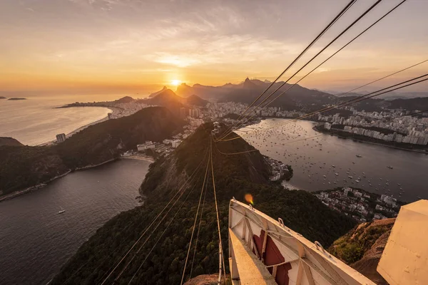 Sugar Loaf dağından Rio de Janeiro, Brezilya 'daki tramvaya, şehre ve okyanusa güzel altın gün batımı manzarası