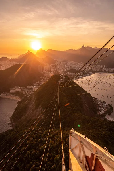 Sugar Loaf dağından Rio de Janeiro, Brezilya 'daki tramvaya, şehre ve okyanusa güzel altın gün batımı manzarası