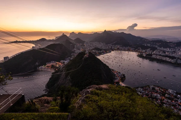 Sugar Loaf dağından Rio de Janeiro, Brezilya 'daki tramvaya, şehre ve okyanusa güzel altın gün batımı manzarası