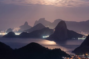 Rio de Janeiro, Brezilya 'da gece okyanus ve karanlık dağ siluetleri için güzel bir manzara
