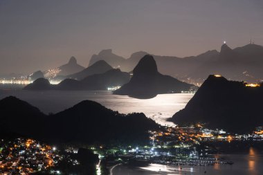 Rio de Janeiro, Brezilya 'da gece okyanus ve karanlık dağ siluetleri için güzel bir manzara
