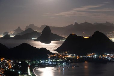 Rio de Janeiro, Brezilya 'da gece okyanus ve karanlık dağ siluetleri için güzel bir manzara