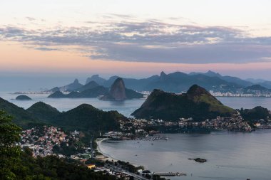 Rio de Janeiro, Brezilya 'da pembe gökyüzü, dağlar ve okyanus için güzel bir gün doğumu manzarası