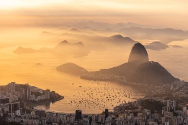Rio de Janeiro, Brezilya 'da renkli gündoğumu bulutlarıyla şehre, dağlara ve okyanusa güzel bir manzara