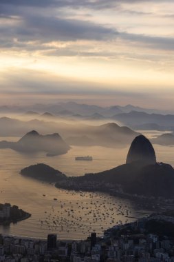 Rio de Janeiro, Brezilya 'da renkli gündoğumu bulutlarıyla şehre, dağlara ve okyanusa güzel bir manzara