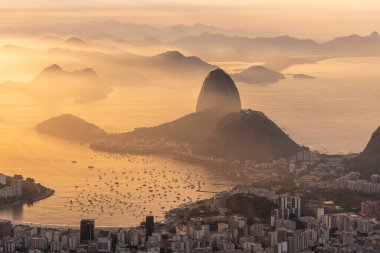 Rio de Janeiro, Brezilya 'da renkli gündoğumu bulutlarıyla şehre, dağlara ve okyanusa güzel bir manzara
