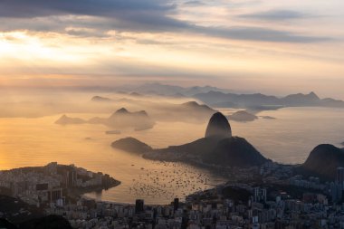 Rio de Janeiro, Brezilya 'da renkli gündoğumu bulutlarıyla şehre, dağlara ve okyanusa güzel bir manzara