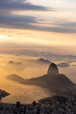 Rio de Janeiro, Brezilya 'da renkli gündoğumu bulutlarıyla şehre, dağlara ve okyanusa güzel bir manzara