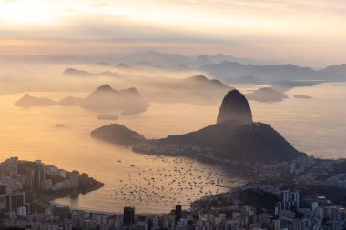 Rio de Janeiro, Brezilya 'da renkli gündoğumu bulutlarıyla şehre, dağlara ve okyanusa güzel bir manzara