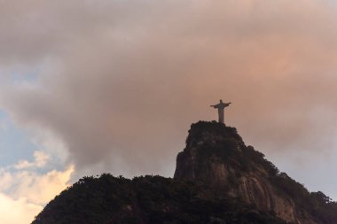 Dağın tepesinde renkli turuncu günbatımı bulutlarıyla İsa Heykeli 'nin güzel manzarası, Rio de Janeiro, Brezilya