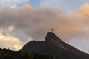 Dağın tepesinde renkli turuncu günbatımı bulutlarıyla İsa Heykeli 'nin güzel manzarası, Rio de Janeiro, Brezilya