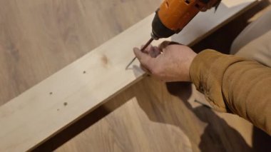 Cordless Screwdriver screws a screw into a wooden beam,