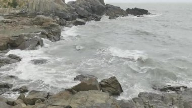 Dev dalga yavaş çekimde kayaya çarpıyor ve her yere su püskürtüyor. Yüksek kalite 4k görüntü