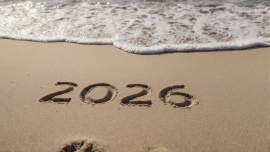 2026 yılı bir kumsaldaki kumsalda yazılıdır ve bir dalga onu alıp götürmek için yaklaşır..