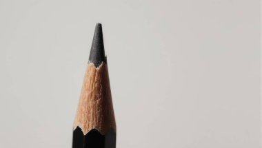 A detailed macro shot of a sharpened pencil tip, showcasing the graphite and wood texture against a plain backdrop, emphasizing precision and detail.