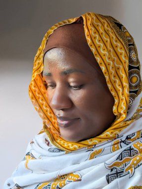 Canlı, geleneksel türbanlı, yumuşak ışığa bakan Afrikalı bir kadının sakin portresi. Duyguları, güzelliği, kültürü ve zarif kadınlığı yakalar..