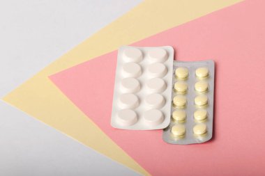 Beyaz ve sarı ilaçlar çok renkli arka planda yatar. Çok renkli arka planda farklı haplar var.