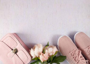 Eşyalar, ahşap arka planda, leylak renginde serilmiş. Küçük pembe bir çanta ve hafif yaz ayakkabıları. Düzen masanın üzerinde..