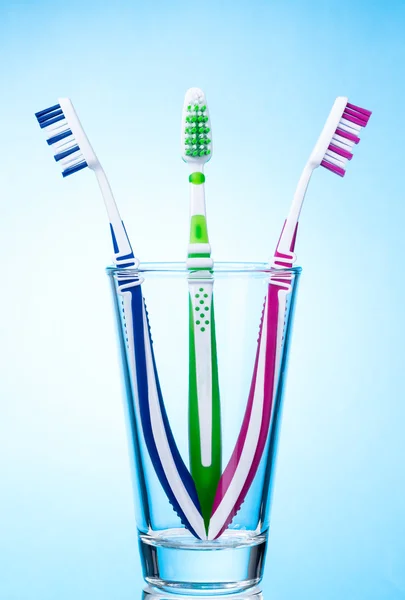 Cepillos de dientes en vidrio sobre fondo azul — Foto de Stock