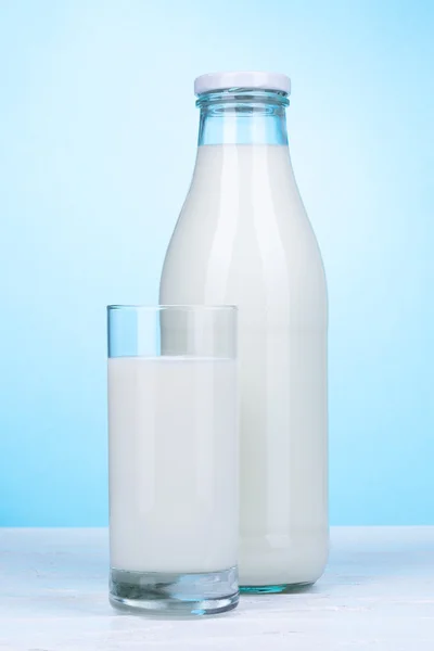 Fles en glas melk op lichte blauwe achtergrond. — Stockfoto