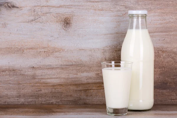 Lapte într-un pahar și sticlă pe fundal din lemn . — Fotografie, imagine de stoc
