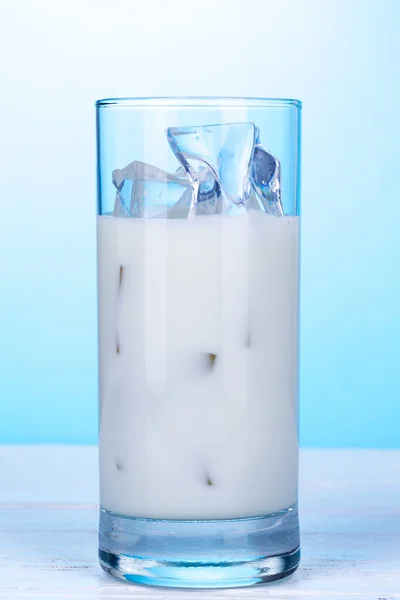 Sticlă de lapte cu cuburi de gheață pe fundal albastru deschis . — Fotografie, imagine de stoc