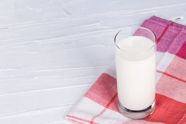 Bicchiere di latte su asciugamano da cucina e sfondo in legno . — Foto Stock