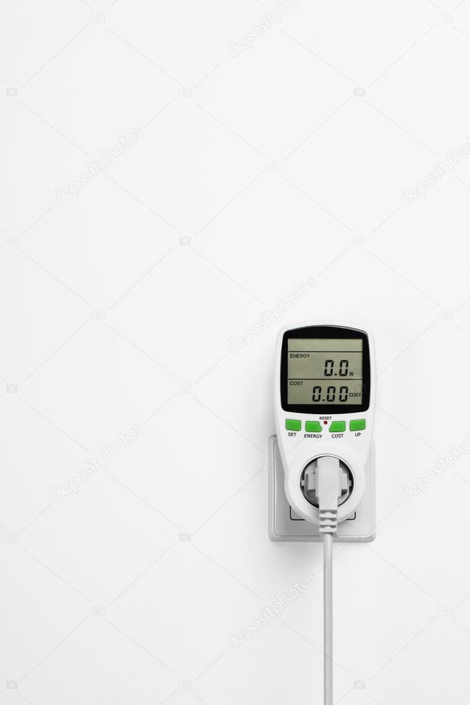 Electric power consumption meter on white wall.