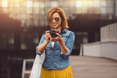 Woman photographer adjusting camera settings and looking at the display