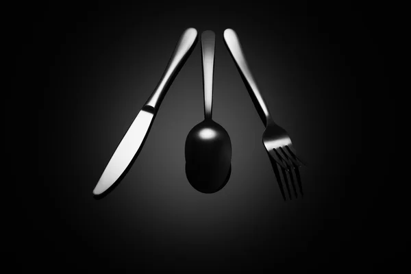 Schwarzer Lebensmittelhintergrund mit Messer, Gabel und Löffel — Stockfoto