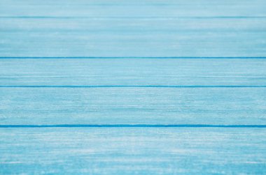 Mavi boyalı pastel ahşap arka planda görünür bir doku var.