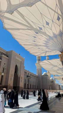 Medine, Suudi Arabistan - 6 Mart 2024: Seyyahlar, Hz. Muhammed el-Mecid an-Nabawi 'nin ana camisine dev şemsiyeler altında yürür ve namaz kılmaya hazırlanırlar..