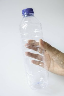 Beyaz arka planda plastik maden suyu şişesi tutan eller.
