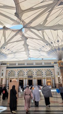 Medine, Suudi Arabistan - 6 Mart 2024: Seyyahlar, Hz. Muhammed el-Mecid an-Nabawi 'nin ana camisine dev şemsiyeler altında yürür ve namaz kılmaya hazırlanırlar..