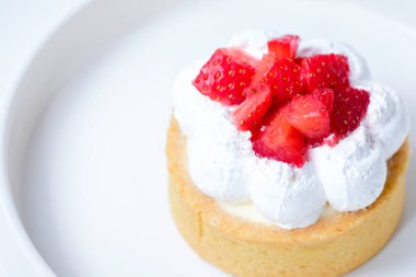 Beyaz tabakta çilekli peynirli tart.