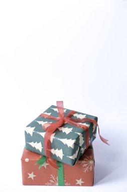 Beyaz arka planda kırmızı ve yeşil renkli kurdeleli bir Noel hediyesi.