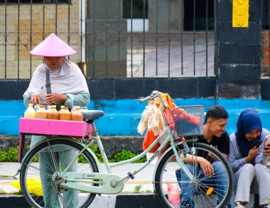 Pekanbaru, Endonezya - 28 Eylül 2025: Otomobilsiz Gününde bisikletini kaldırıma park etmiş geleneksel bir bitkisel içecek satıcısı