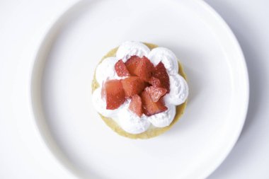 Beyaz tabakta çilekli peynirli tart.